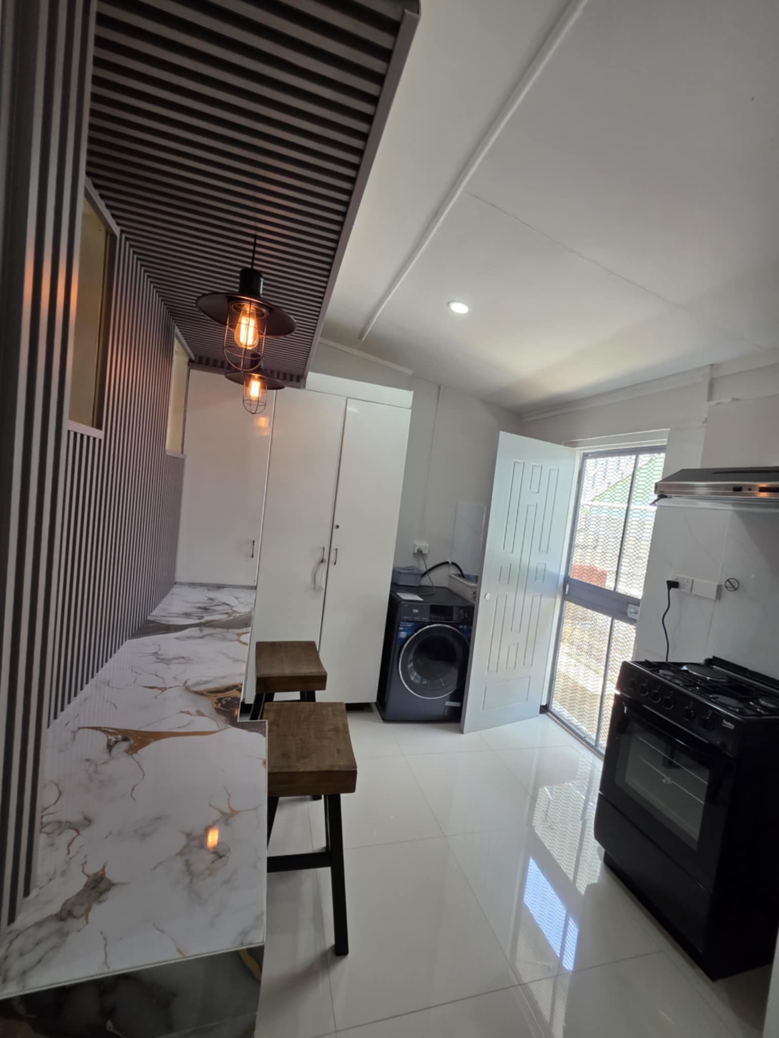 Kitchen with marble-look bench, oven and washing machine